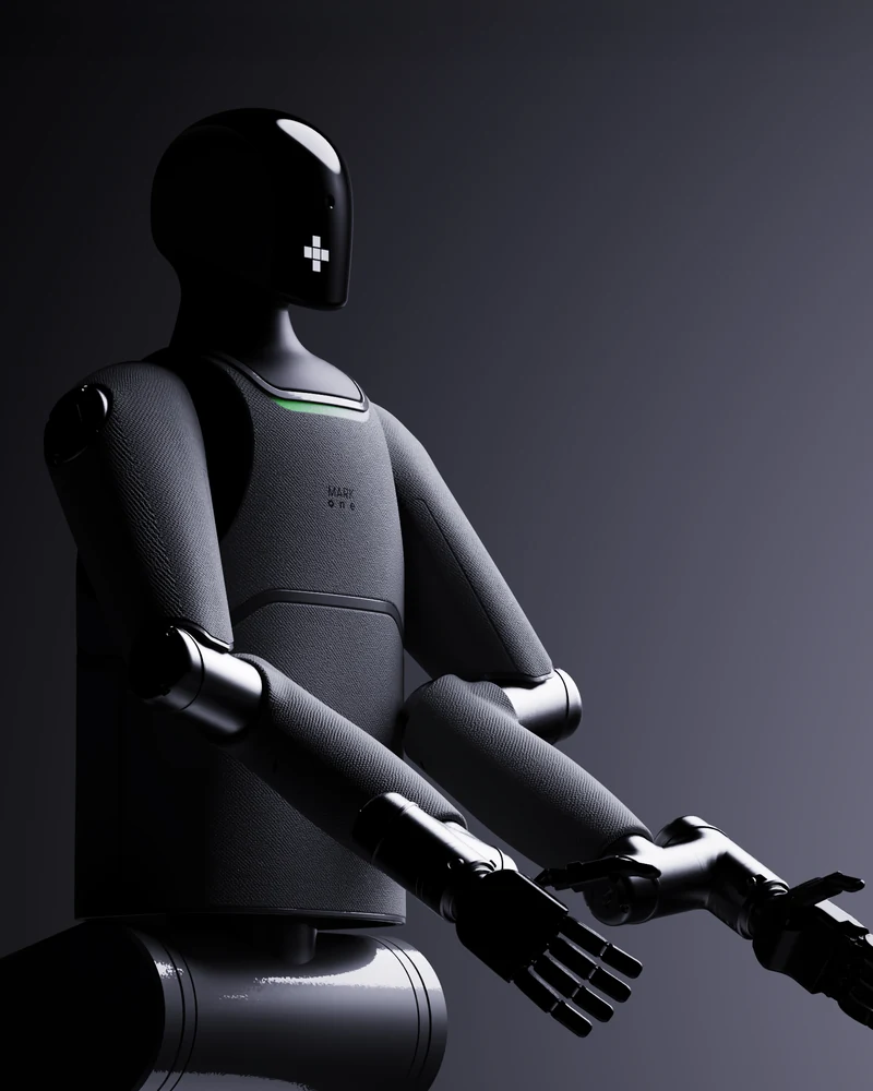 MARK One seated on its base, arms reaching forward, in a dark studio